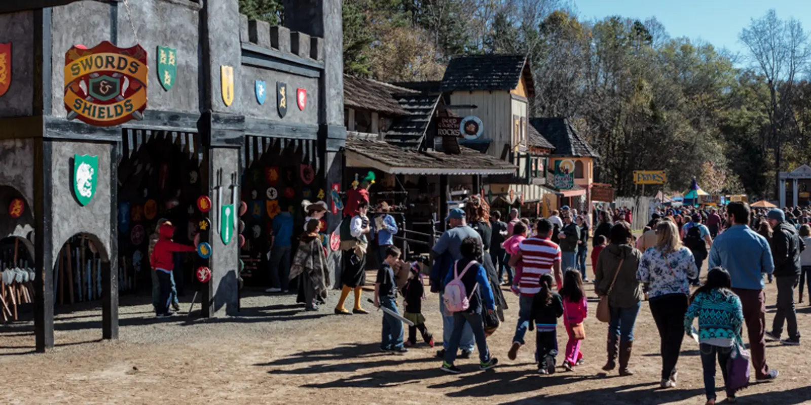 Crowds walking past the castle-front shops of the Carolina Renaissance Festival village in Huntersville on an autumn weekend