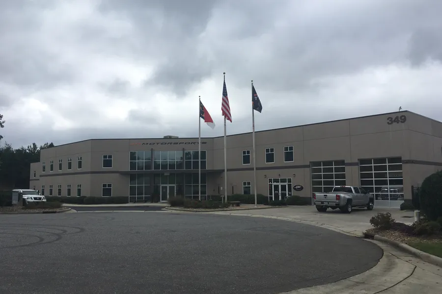 Exterior entrance and glass facade of the JR Motorsports race shop in Mooresville, North Carolina