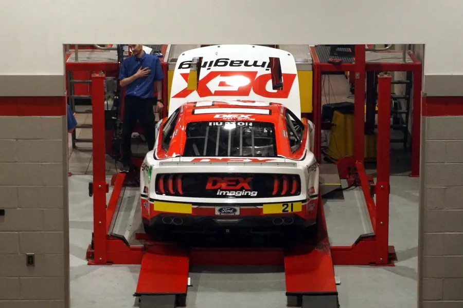 Clean modern shop floor and championship race cars inside the Team Penske racing facility in Mooresville, North Carolina