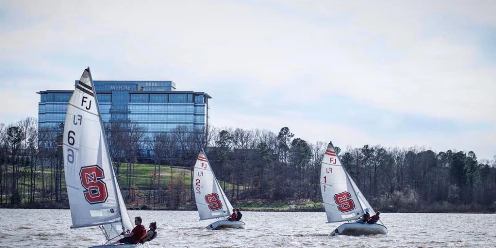 Fleet of sailboats navigating across open lake waters during regional competitive regatta