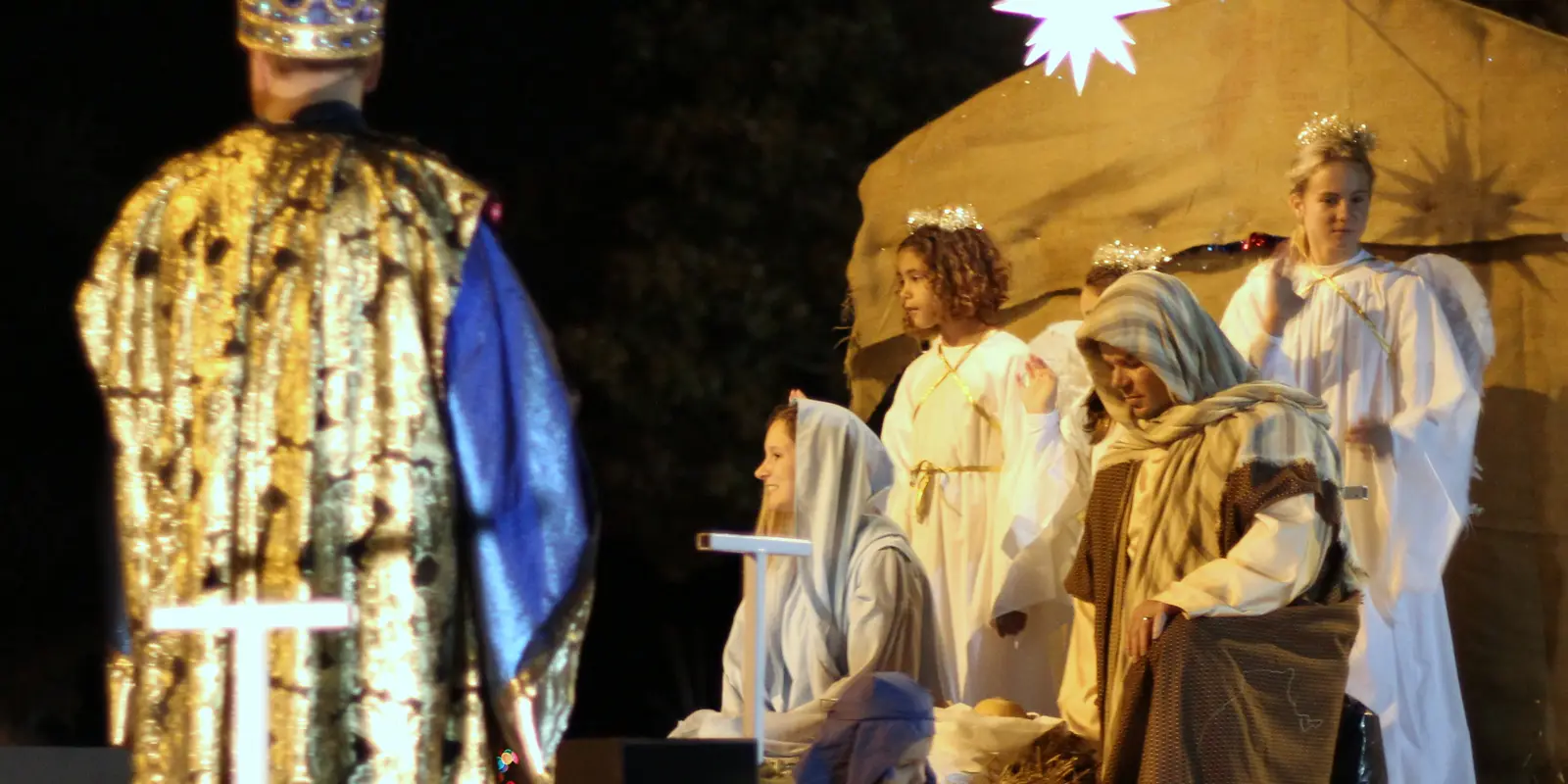 Festive evening holiday community parade with marching performers and glowing festival lights