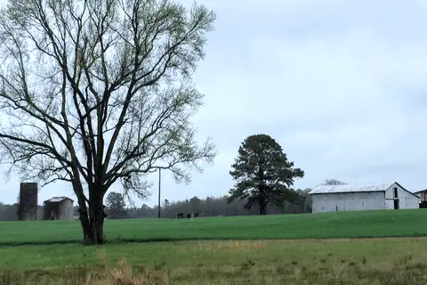 Rustic community barn, wooden equestrian fences, and rolling green pastures in the pastoral countryside of Marvin, North Carolina