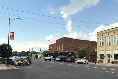 Historic brick storefronts, sidewalks, and tree-lined streetscape of Main Street in downtown Mocksville