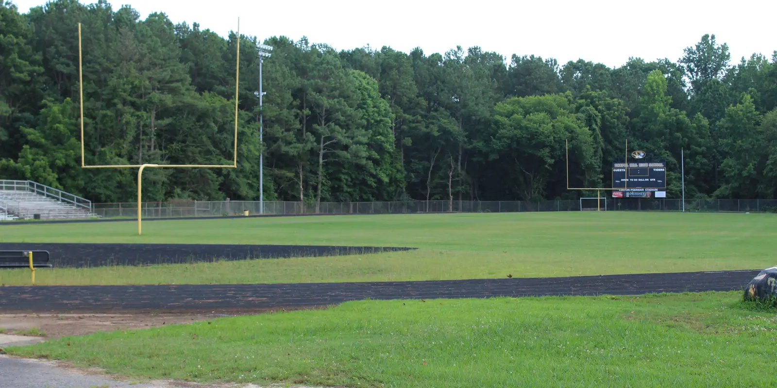 Outdoor athletic stadium track and football field under clear skies for high school championship games