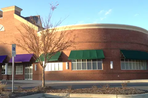 Curved red brick commercial facade and landscaped retail grounds of Wesley Chapel Village Commons in Wesley Chapel, North Carolina