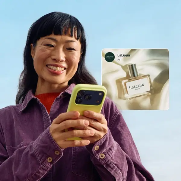 Woman smiling at a product ad on her phone, the discovery moment Meta ads are built for