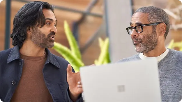 Two business decision-makers discussing a proposal on a laptop