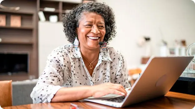 Business owner smiling while reviewing new leads on her laptop