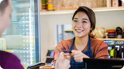 Cafe owner smiling as she takes a card payment from a customer