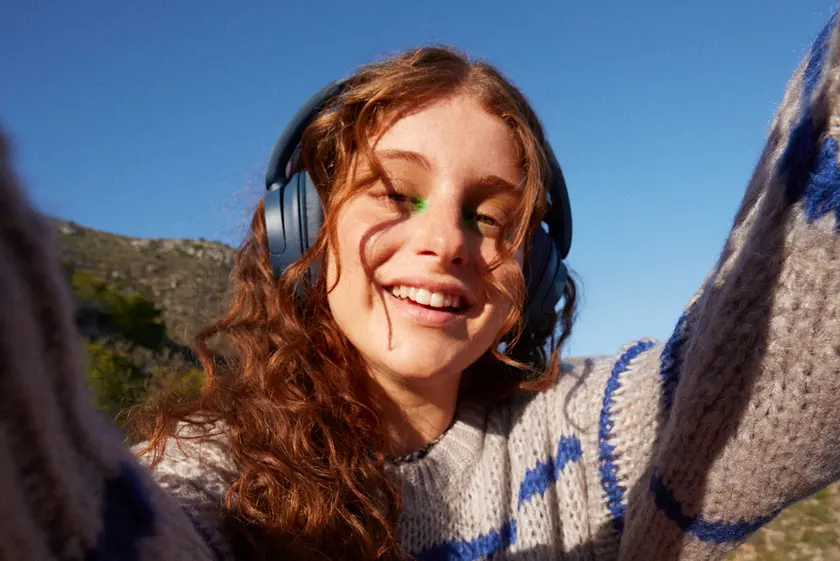Smiling young woman listening to a podcast on headphones outdoors