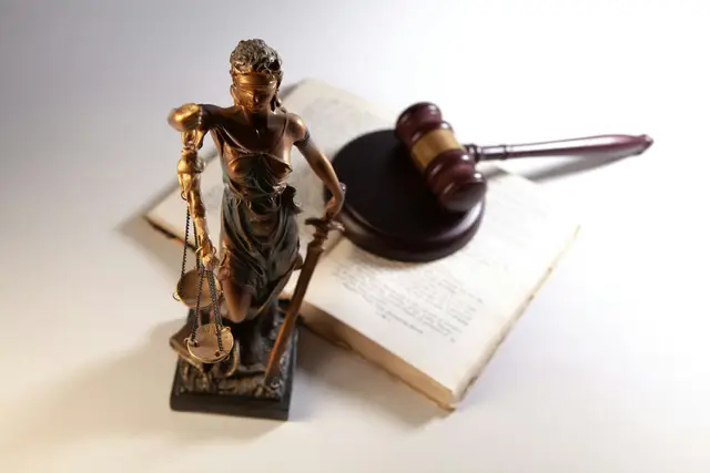 Statue of justice holding scales beside a gavel and an open law book