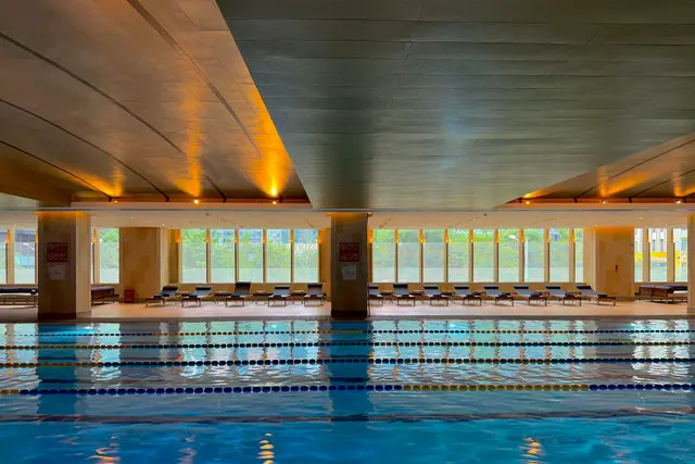 Empty indoor swimming pool with lane ropes under natural light