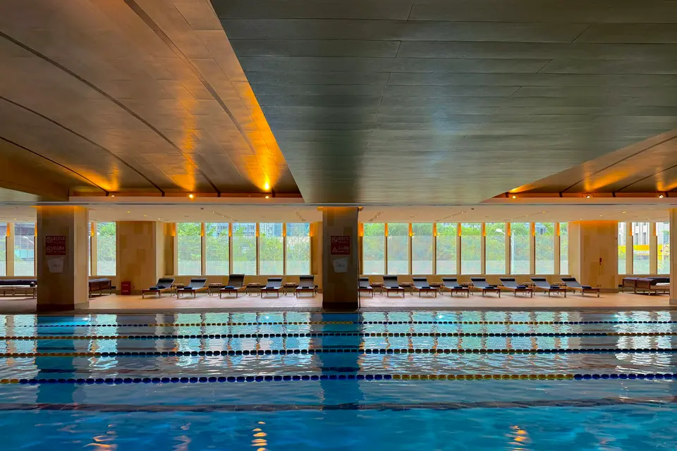 Empty indoor swimming pool with lane ropes under natural light