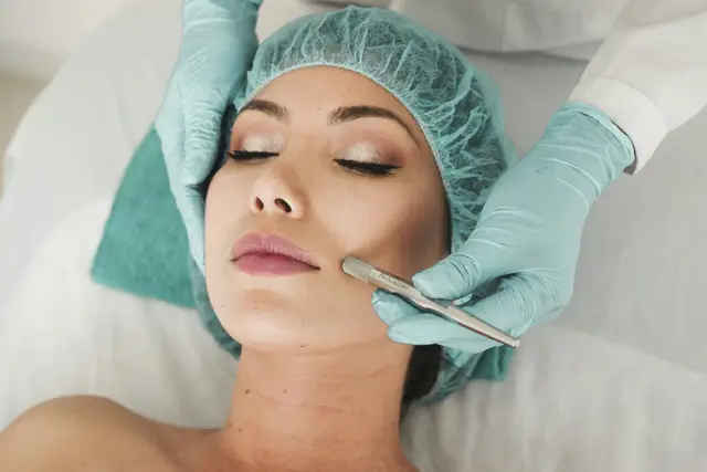 Clinician in gloves giving a woman a facial skin treatment in a bright clinic room