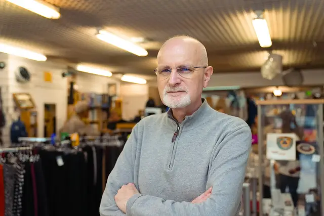 Small business owner standing with arms crossed inside his shop