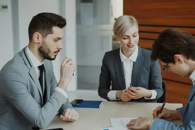 Insurance agent reviewing a policy with two clients at a desk