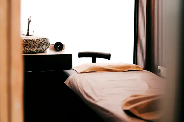 Quiet spa treatment room with a made-up massage table by a window