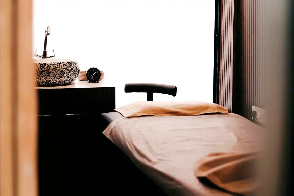 Quiet spa treatment room with a made-up massage table by a window