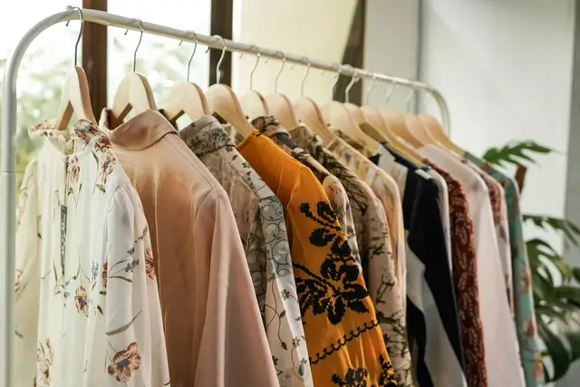 Patterned women’s blouses on wooden hangers on a boutique clothing rack