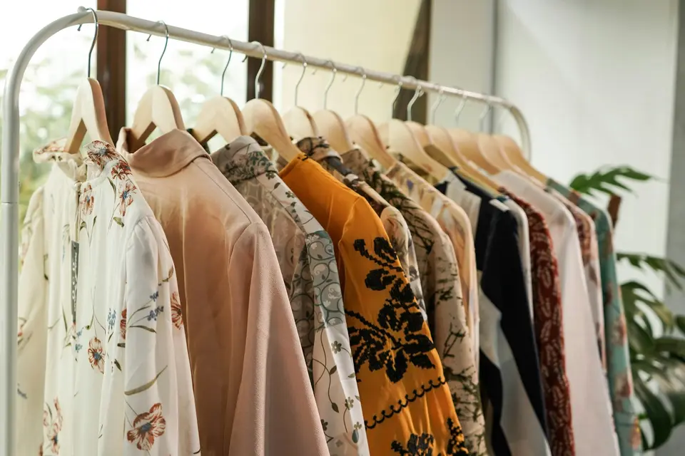 Patterned women’s blouses on wooden hangers on a boutique clothing rack
