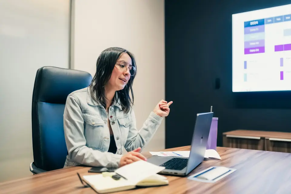 Finance leader presenting spending data from a laptop to a screen in a meeting room