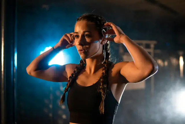 Woman in workout clothes tying back her hair in a gym before training