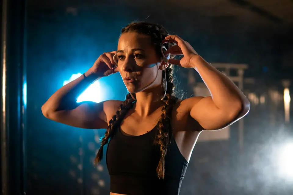 Woman in workout clothes tying back her hair in a gym before training