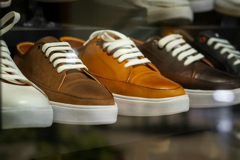 Row of leather sneakers with white laces on a lit store display shelf