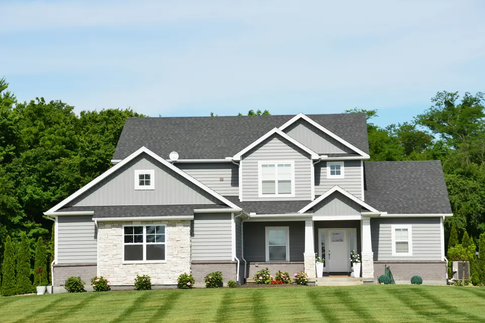 Two-story gray suburban house with a freshly mowed front lawn
