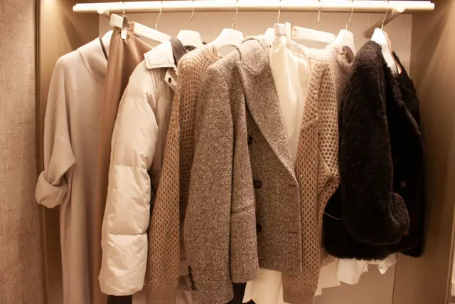 Coats and knitwear in soft neutral tones hanging on a closet rail