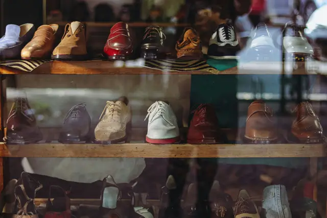 Rows of leather dress shoes, loafers and heels on wooden shelves behind a shop window