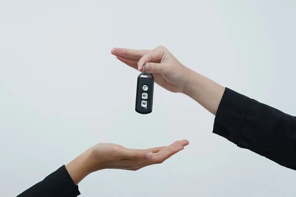 One hand passing a car key to another, the moment a car sale closes