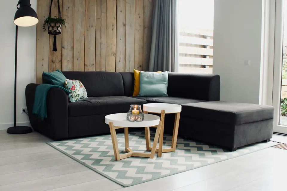Bright living room with a dark sectional sofa, two round coffee tables and a patterned area rug