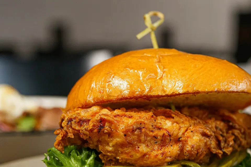 Crispy fried chicken sandwich with pickles and lettuce next to a basket of fries
