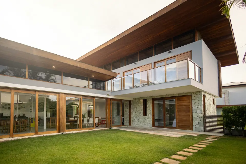 Bright modern home with tall glass doors and large upper windows above a green lawn