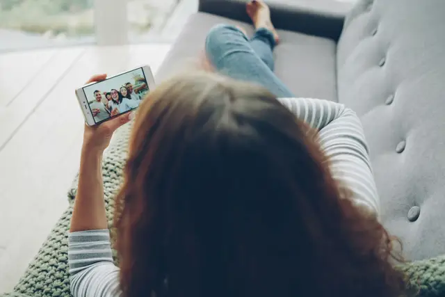 Woman relaxing on a couch watching a video on a phone held sideways