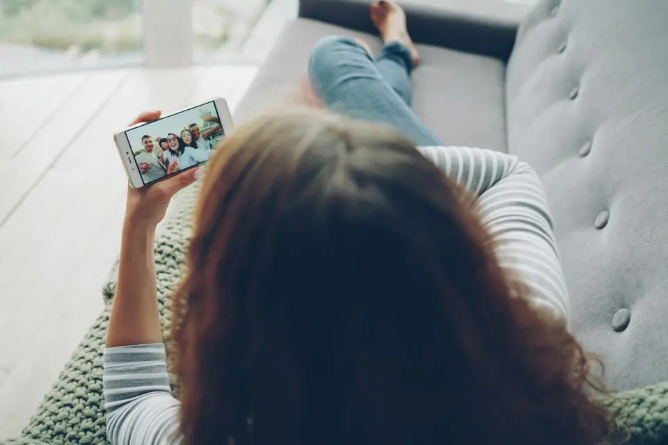 Woman relaxing on a couch watching a video on a phone held sideways