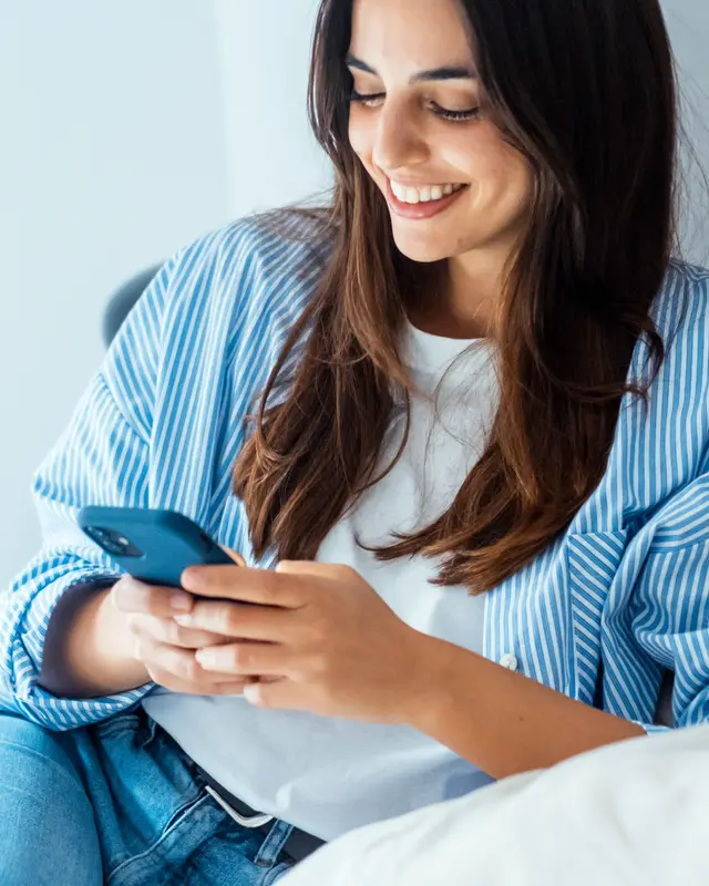 Young woman smiling as she watches a video on her phone