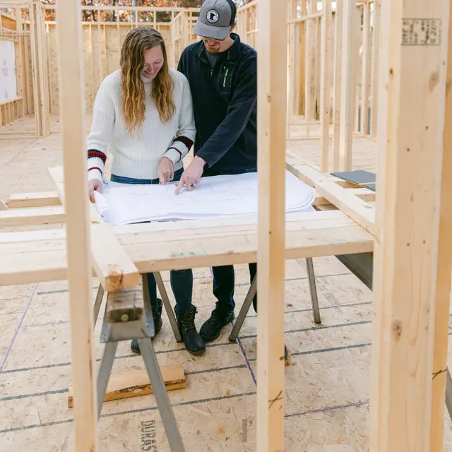 Contractor and homeowner reviewing plans inside a newly framed room
