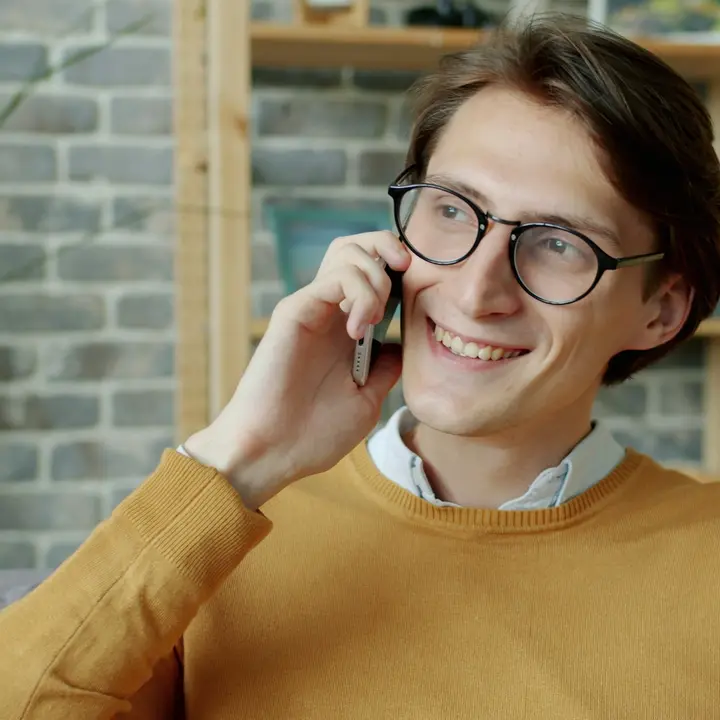 Smiling man calling a business on his phone