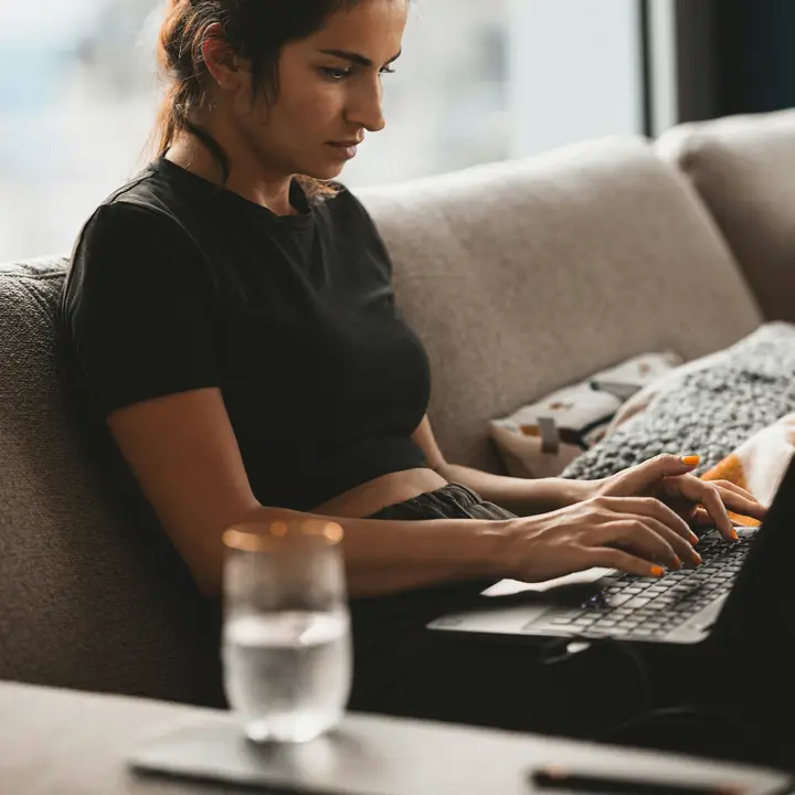 Woman on her couch filling in a contact form on her laptop