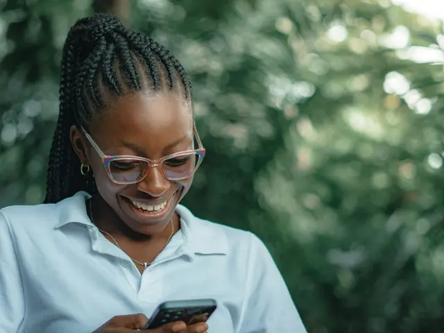 Smiling woman reading a page on her phone outdoors
