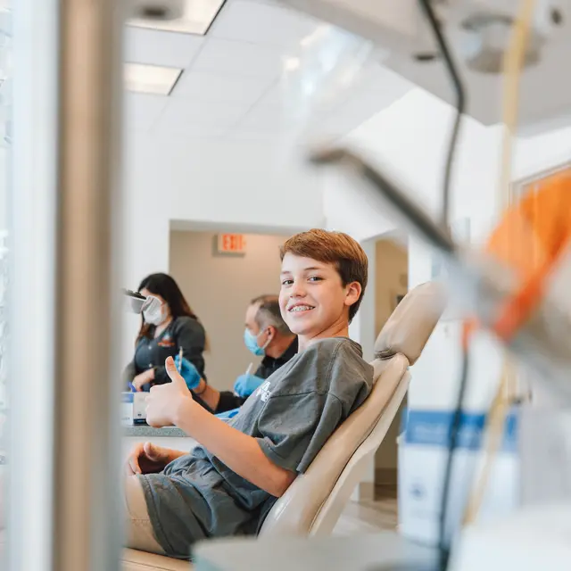 Young patient giving a thumbs up from a dental chair