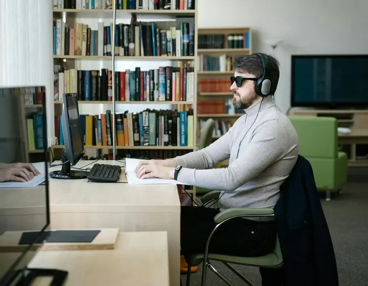 Blind man wearing headphones using a computer with a screen reader
