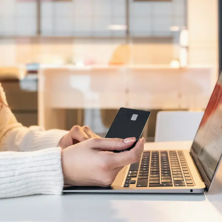 Shopper holding a payment card while checking out on a laptop