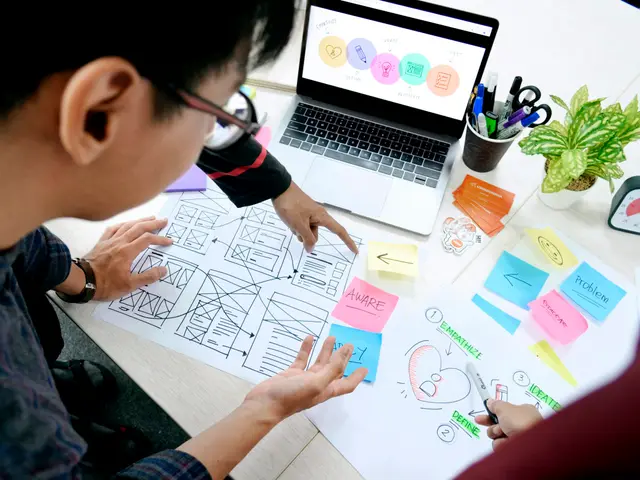 Team sketching website page layouts on paper next to a laptop