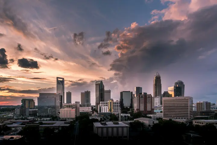 Uptown Charlotte skyline under a dramatic sunset sky