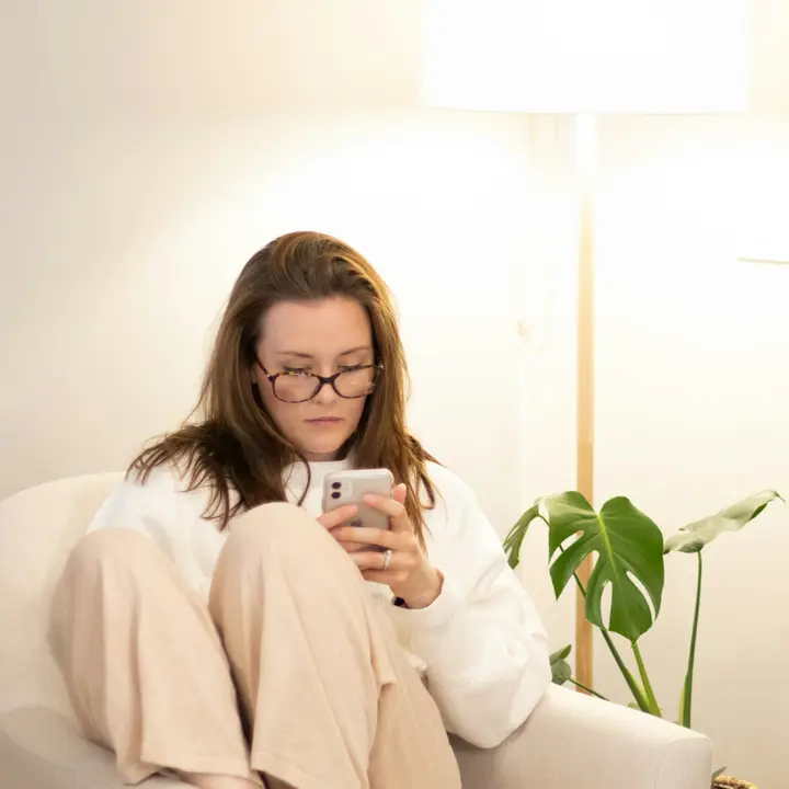 Woman in an armchair reading a business page on her phone